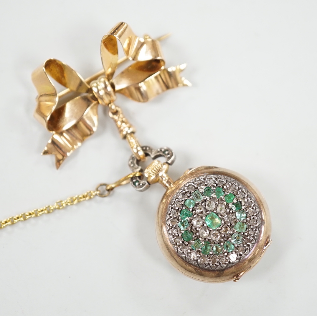 A lady's late 19th century French? yellow metal, emerald and rose cut diamond cluster set fob watch, diameter 24mm, suspended from a late Victorian 9ct gold ribbon bow brooch, gross weight 17.1 grams.